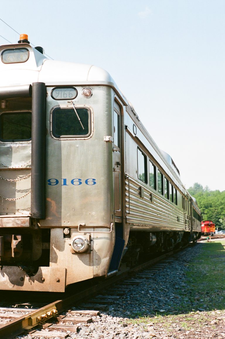 Vintage train on tracks, sunny day.