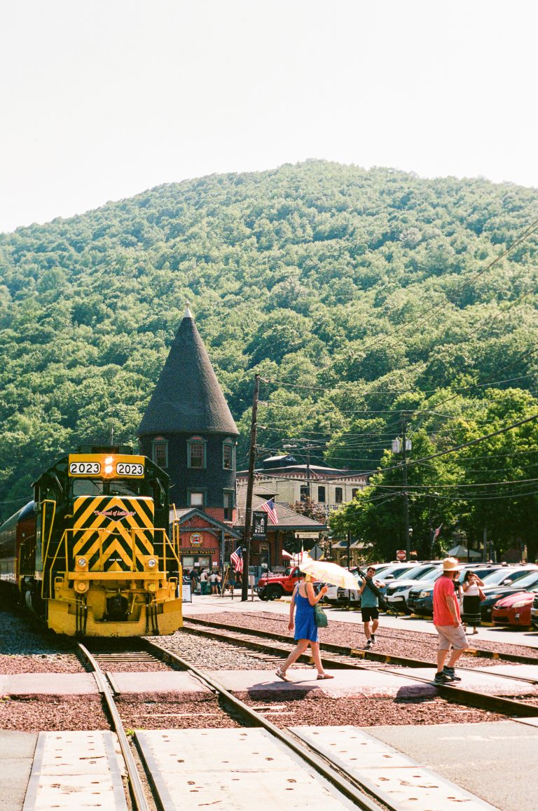 Train passing near mountain and people