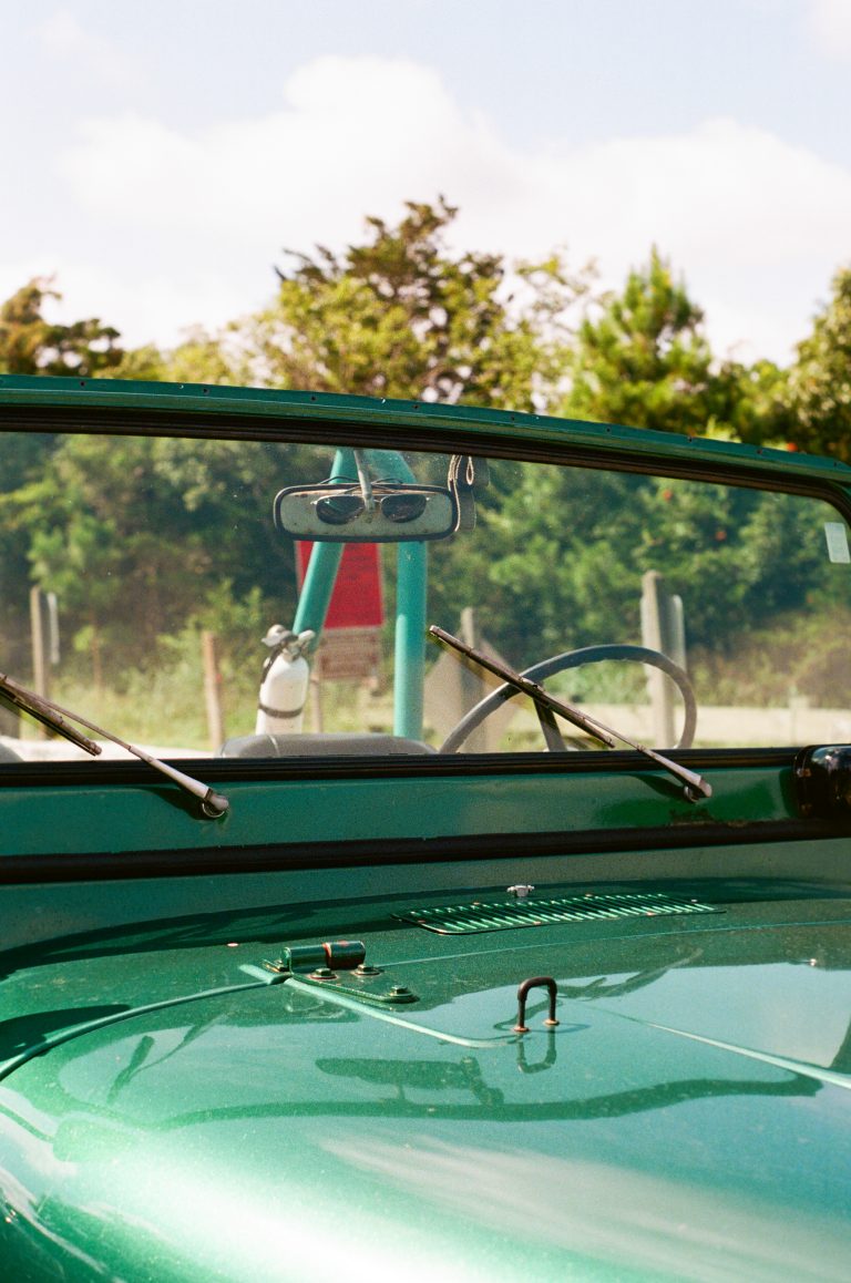 Green convertible with sunglasses reflection