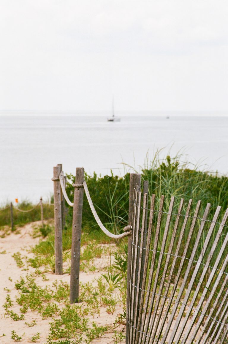 Beach fence with distant sailboat